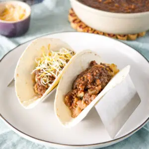 Two flour tortillas in a holder filled with lentils and other taco filling - square