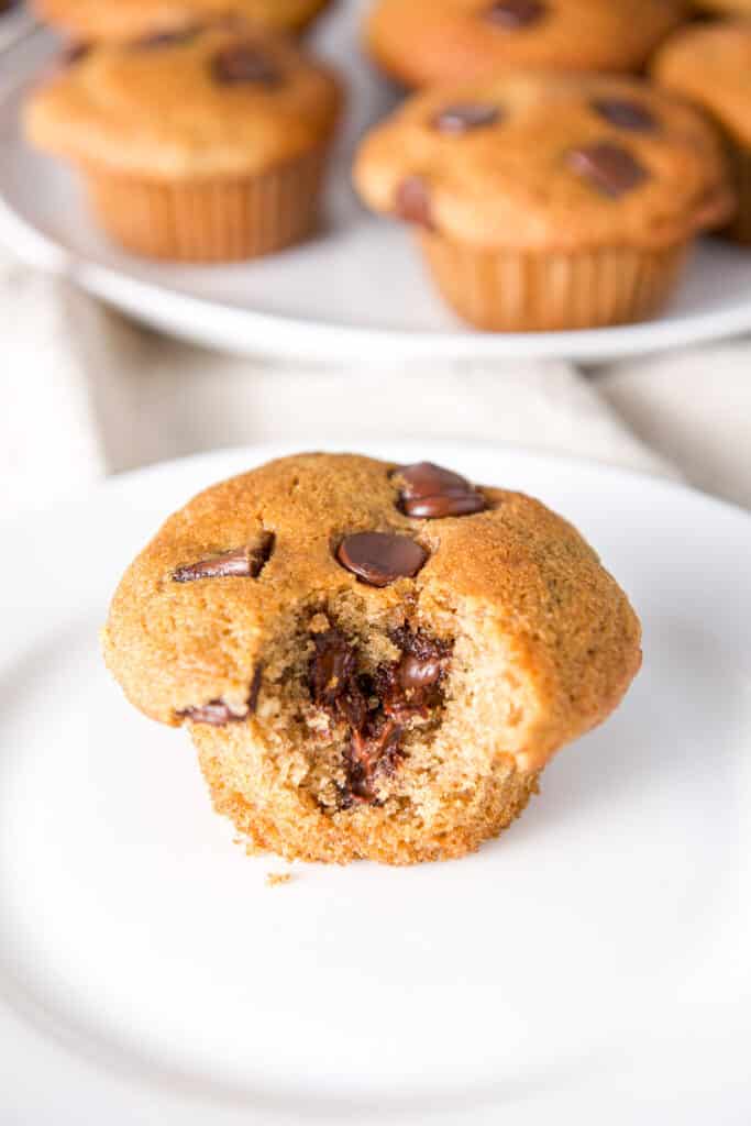 Close up of a white plate with a muffin with a bite taken out looking all gooey