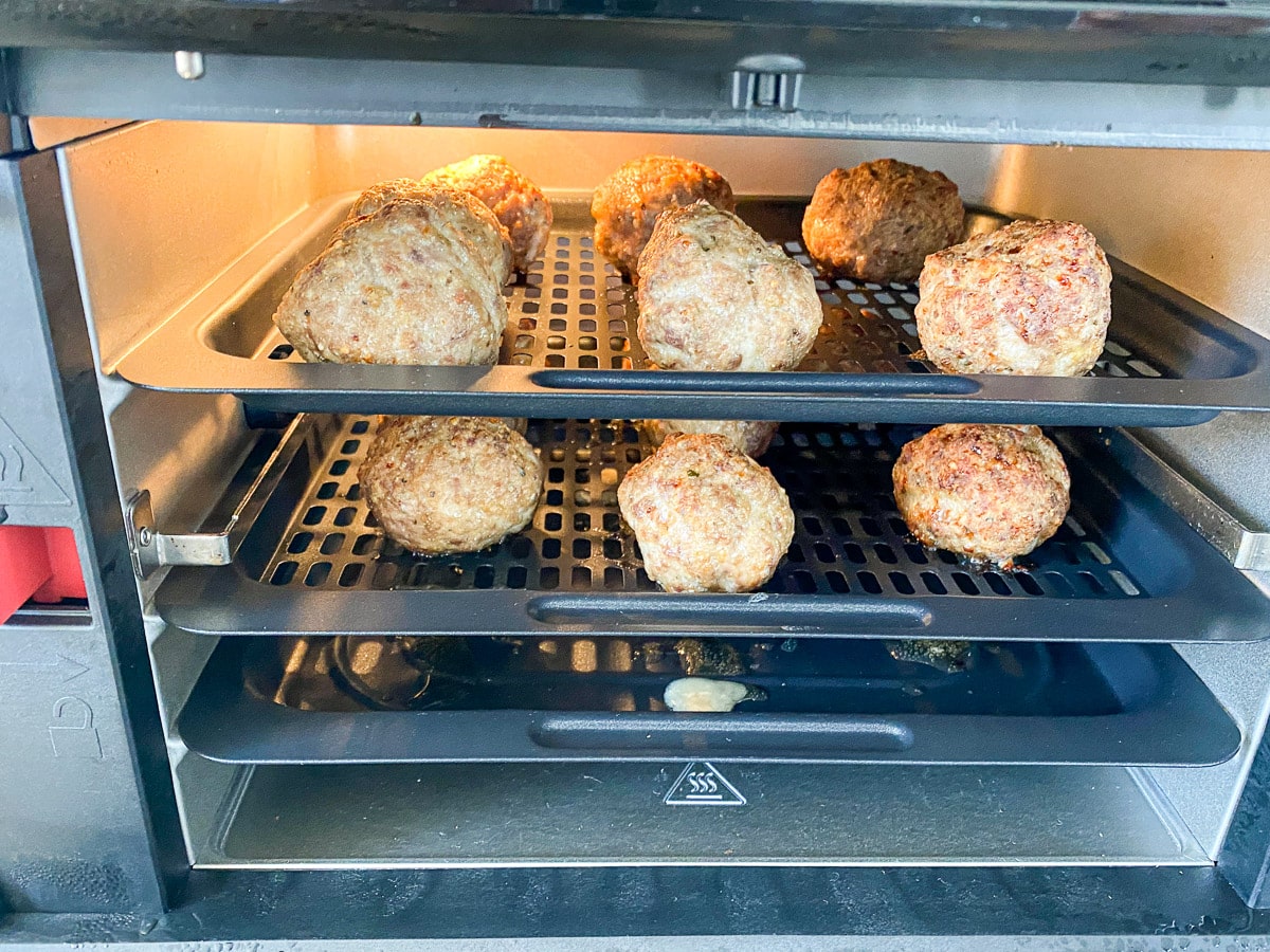 Air fryer open with the meatballs in it cooking