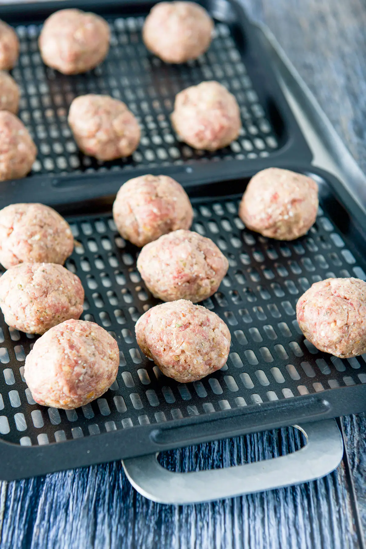Raw meat rolled into balls on two grill trays
