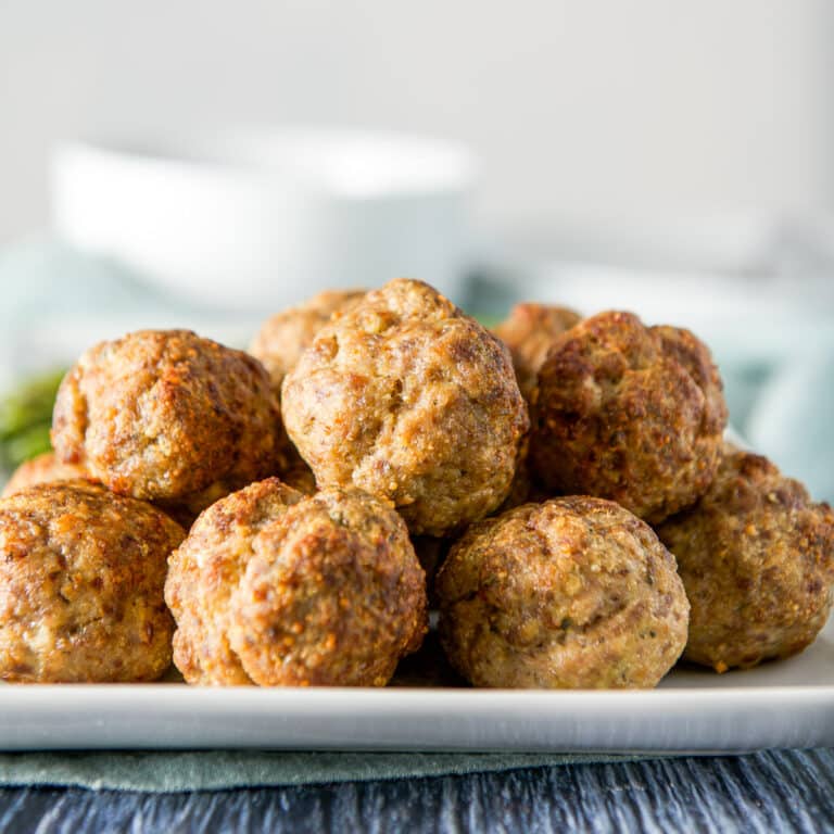 A white plate with a pile of meatballs on it - square
