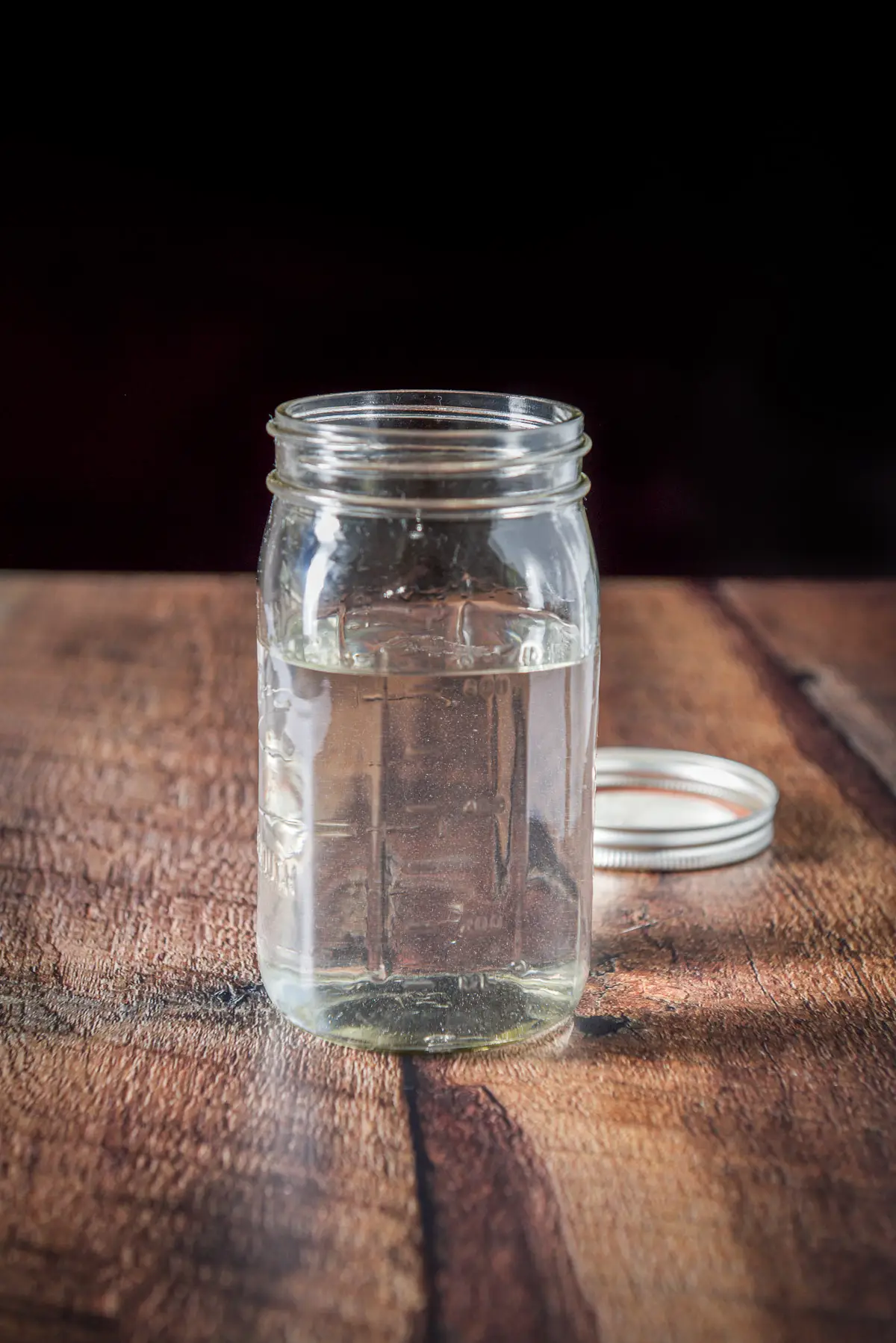 A jar of coconut rum on a table with the lid behind it