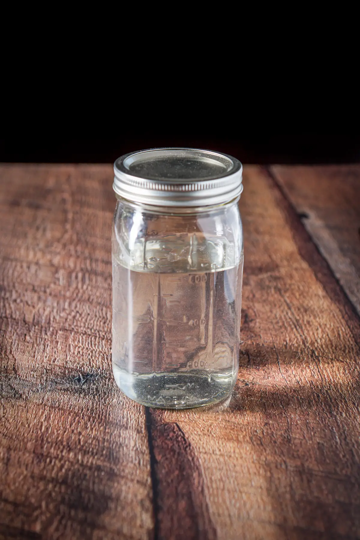 A jar of rum with the lid on it on a wooden table