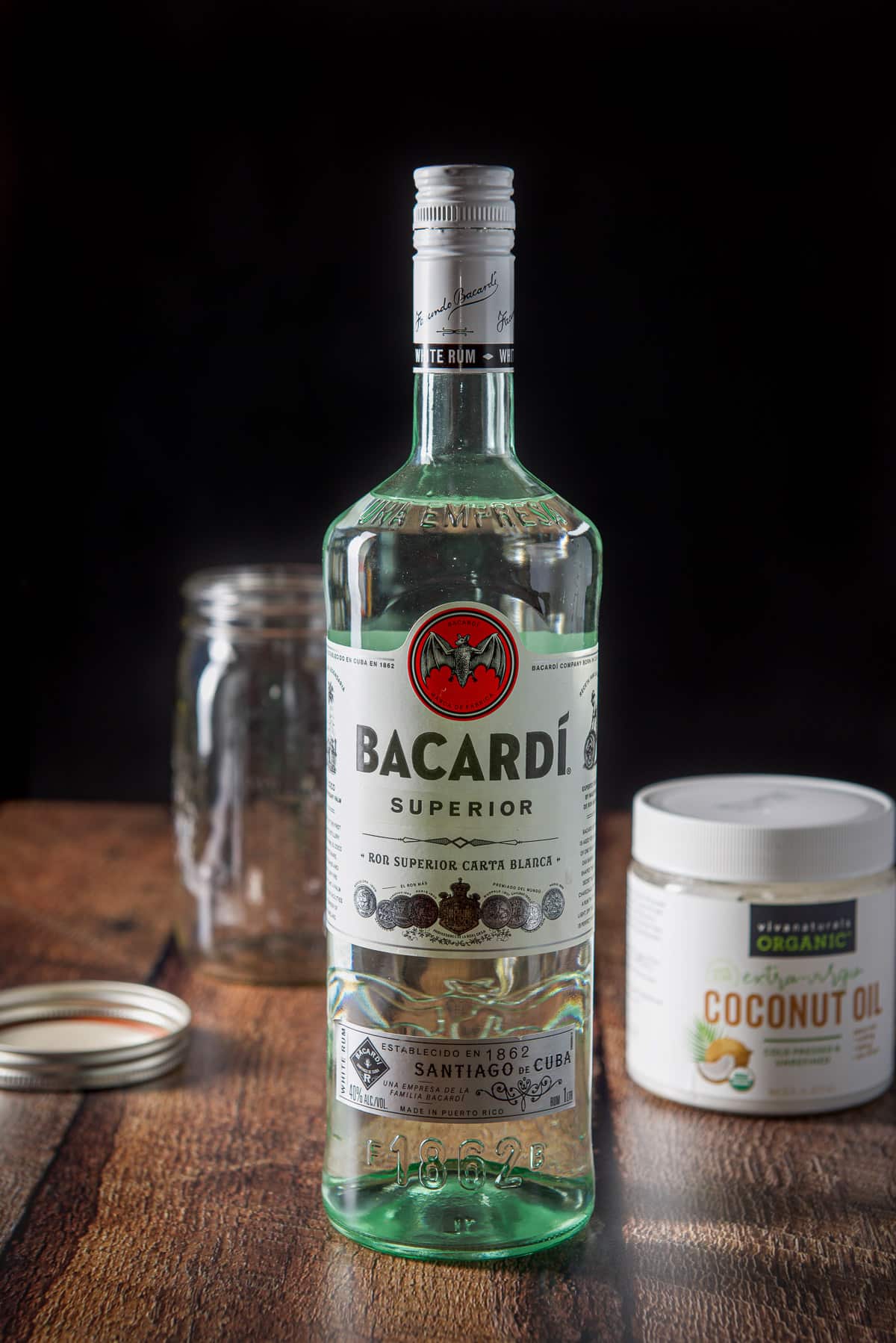 Rum, coconut oil and a jar and lid on a wooden table