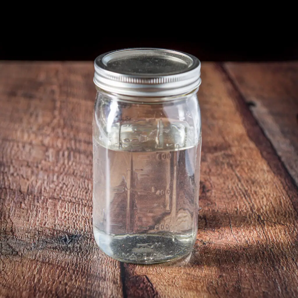 A jar with rum in it on a wooden table - square