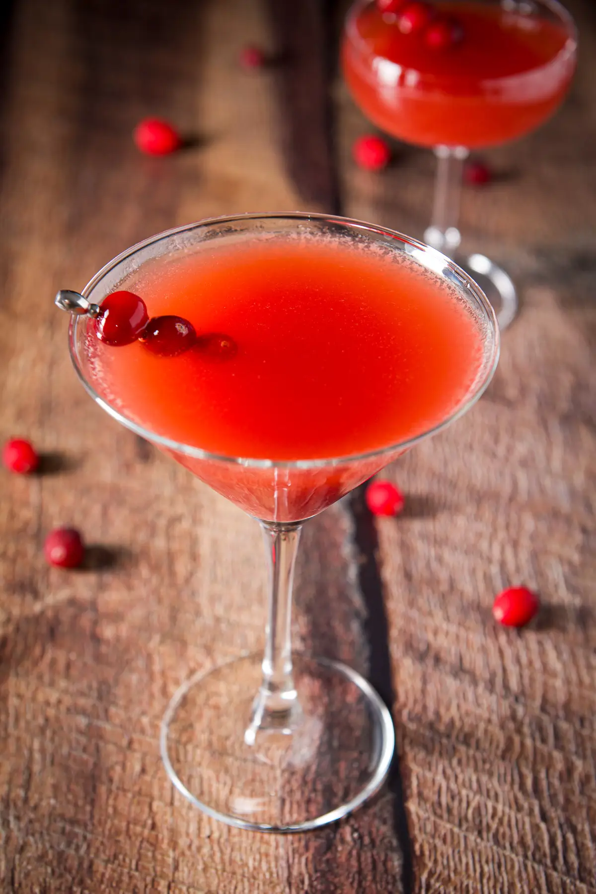 Close view of the cranberry martini with a pick with cranberries on it