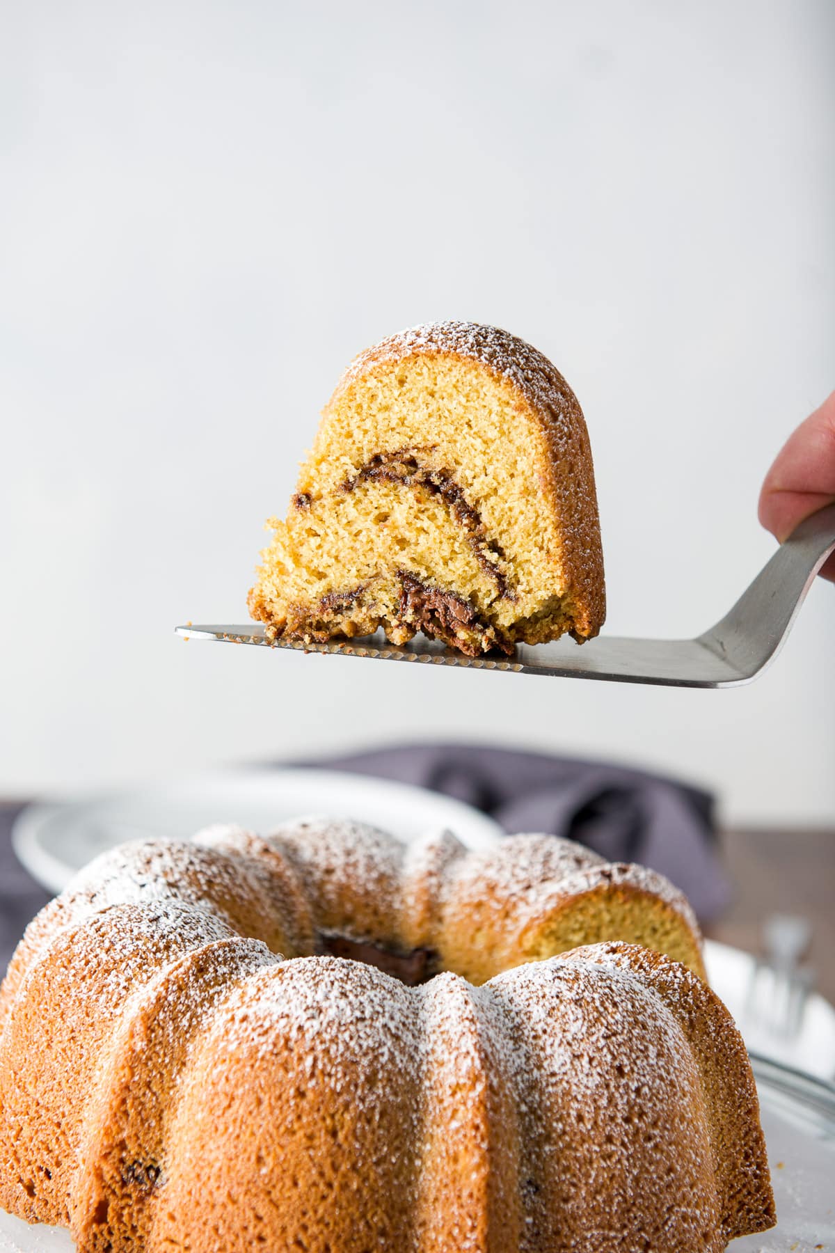 A piece of cake on a cake server held over the coffee cake