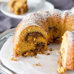 A coffee cake with pieces taken out of it on a cake stand - square
