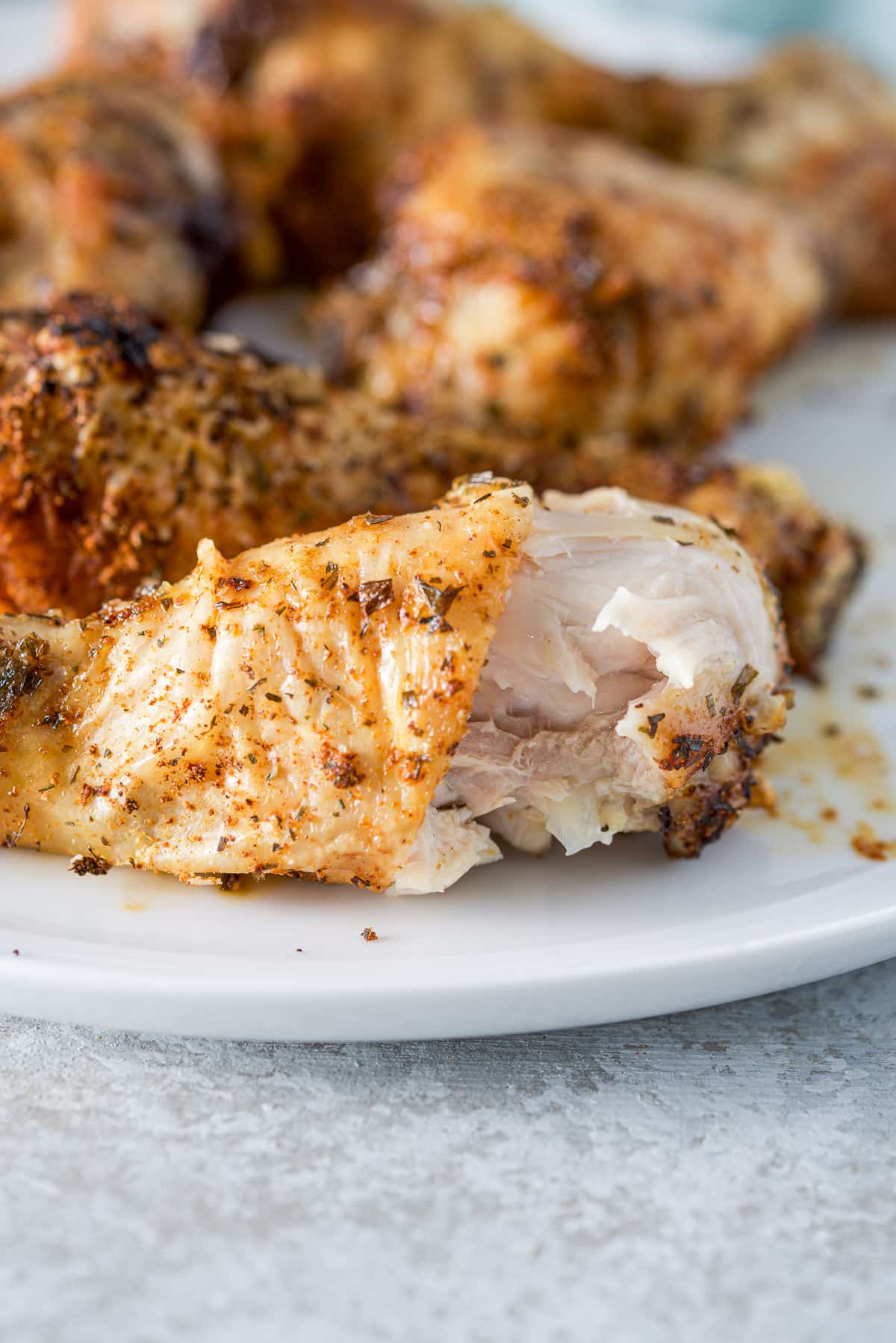 A white plate with drumsticks on it, the front one with a bite taken out of it