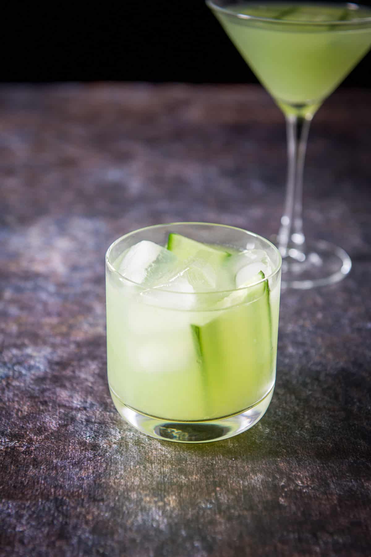 The double old fashioned glass with the cocktail in it with the martini glass in the back