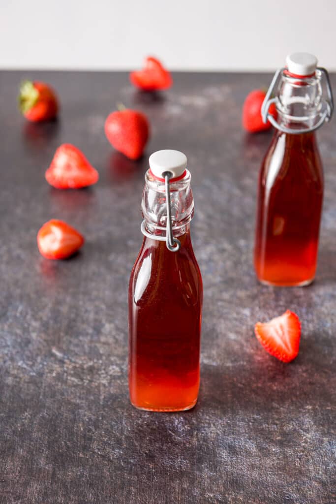 Bottles of red vodka with strawberries on the table