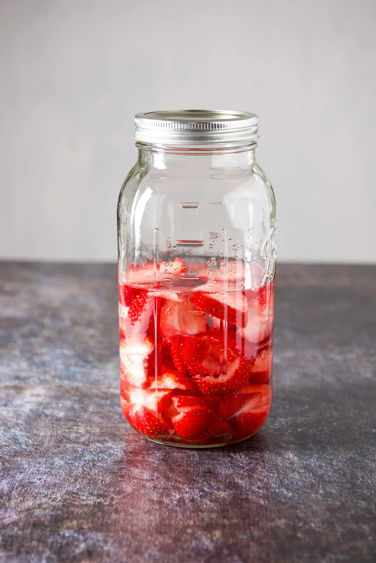 The jar of vodka and strawberries with the lid on and shaken