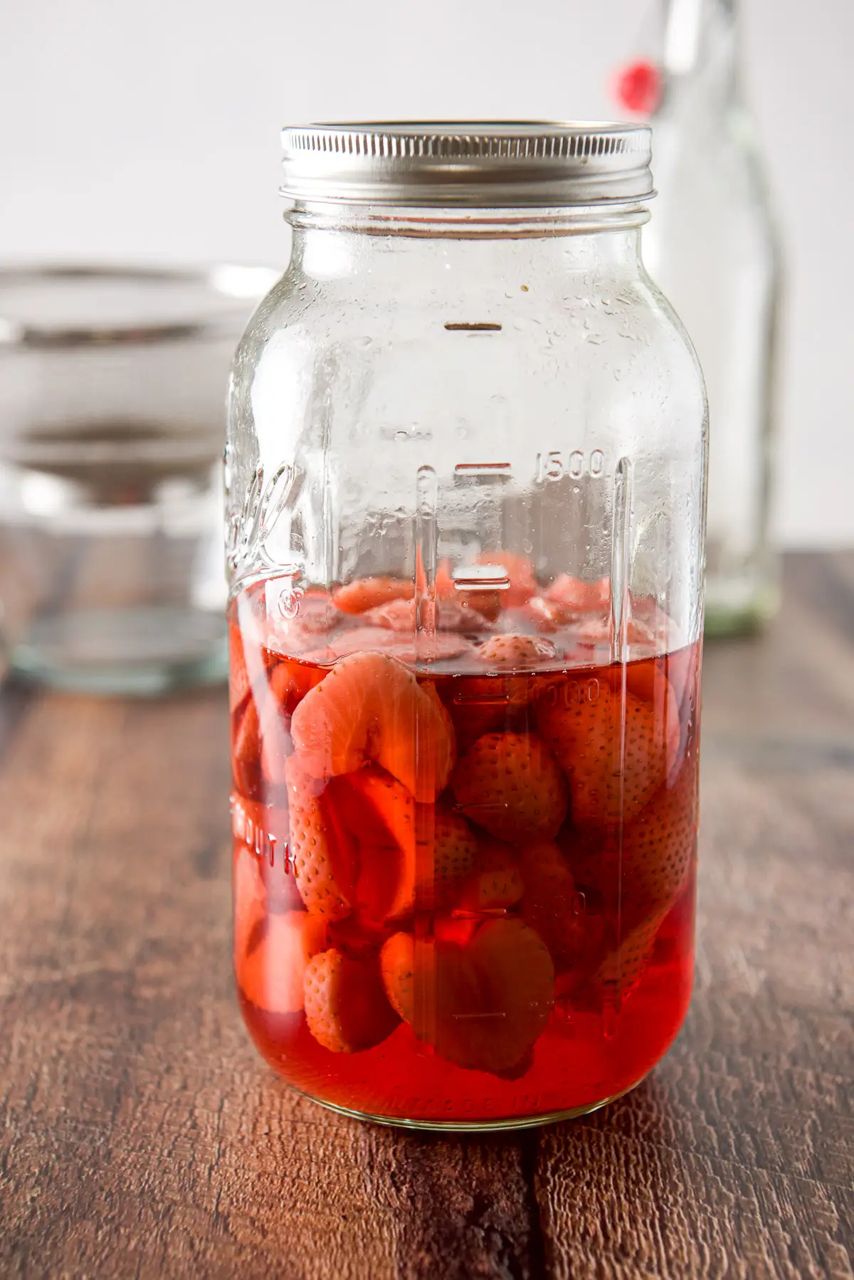The lidded jar with the strawberries and red vodka ready to be strained
