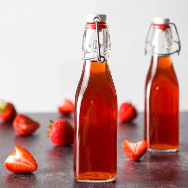 Two bottles with strawberry vodka with strawberries on the table - square