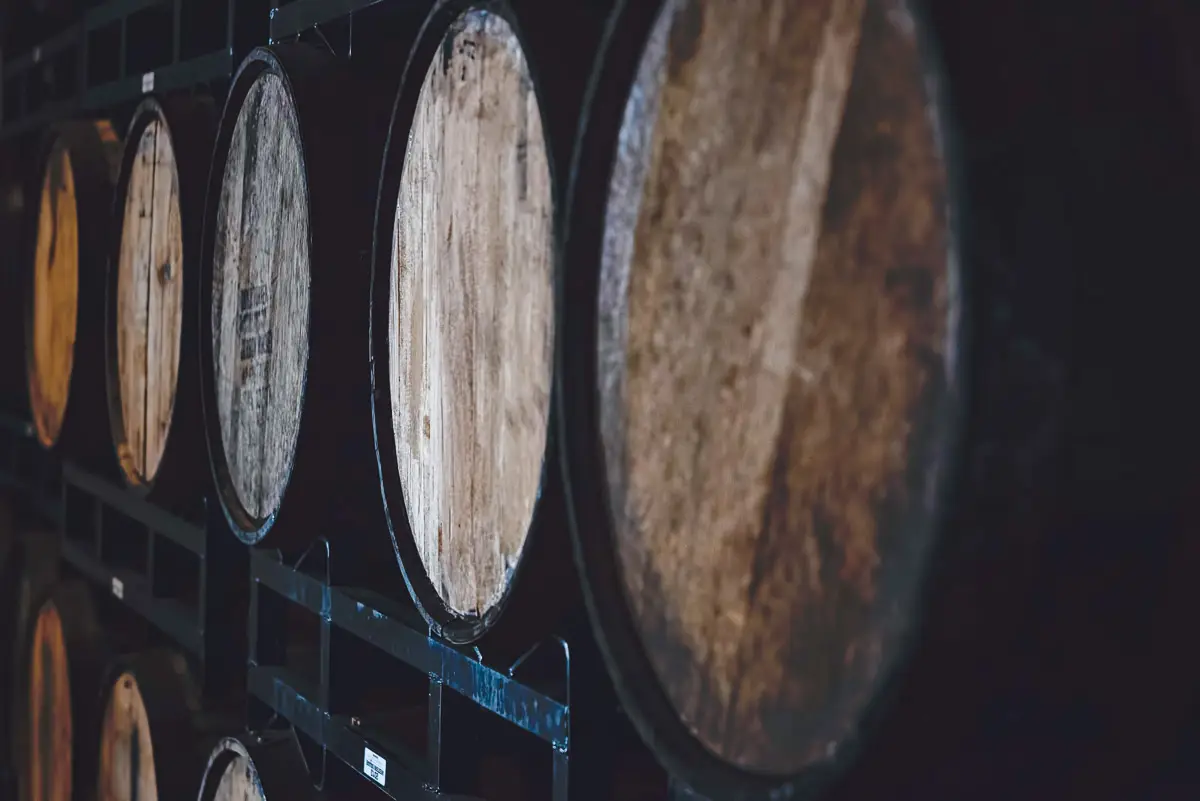 Rows of whiskey filled casks on metal shelves - square