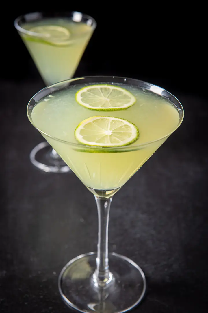 Close up of a lime cocktail in martini glasses with limes floating on the top