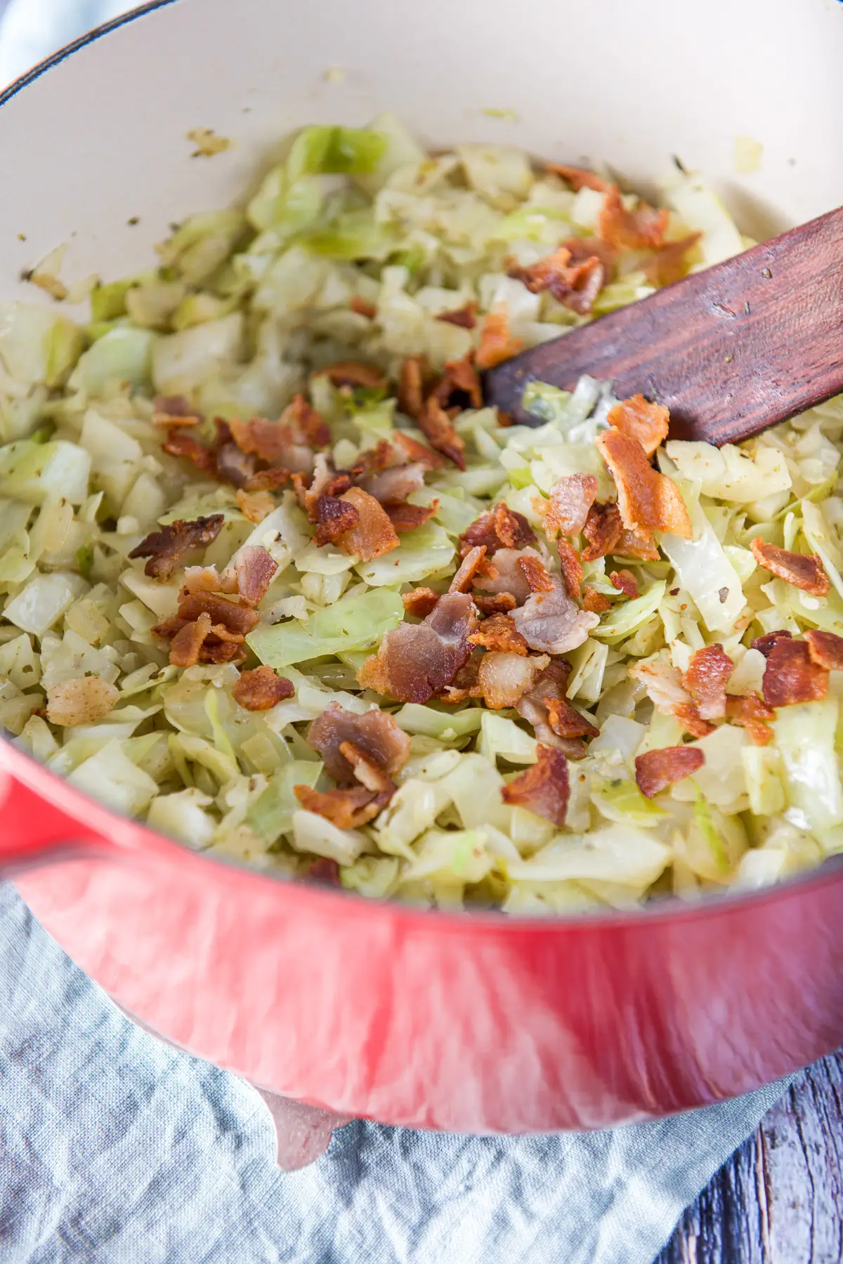 Cooked bacon crumbled on the cooked cabbage in a pan