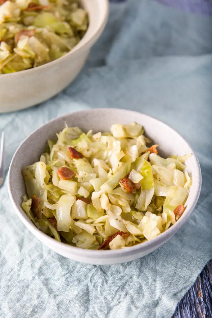 A small grey bowl with the cooked cabbage and the big bowl in the back