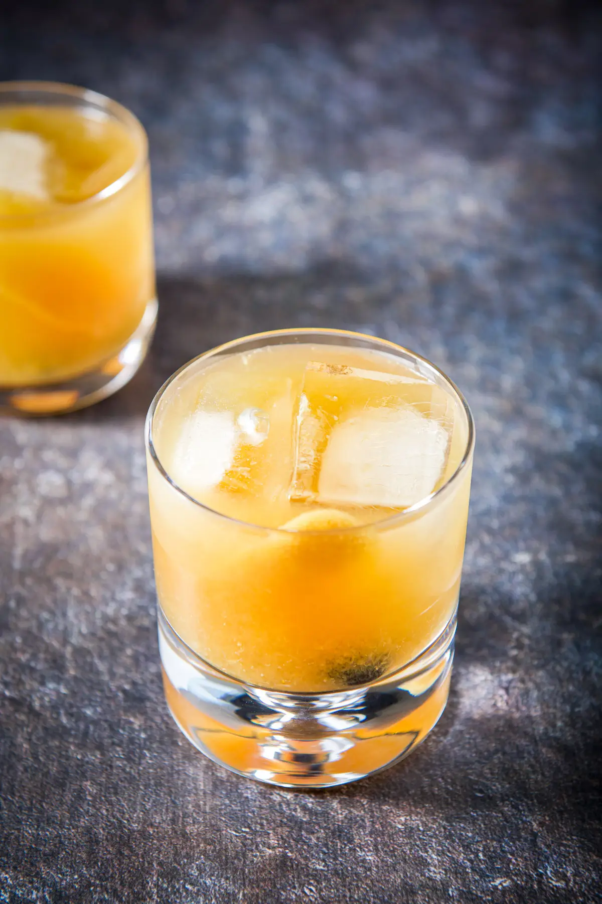 Big ice cubes in the amaretto drink with orange zest garnish