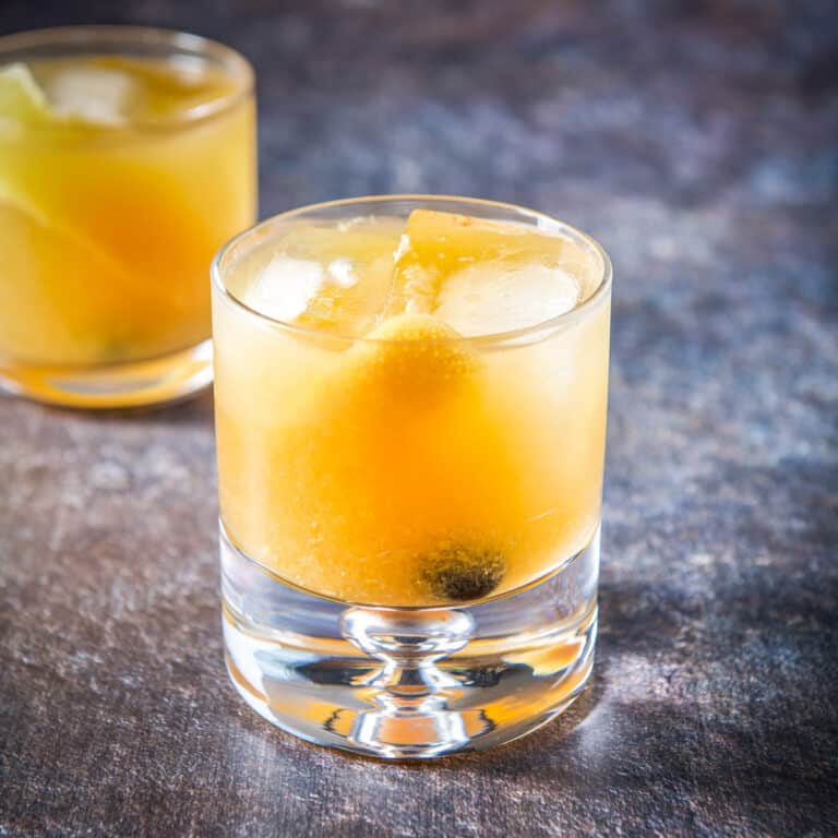 A bubble glass filled with the amaretto cocktail, with the other old fashioned glass in the back -square