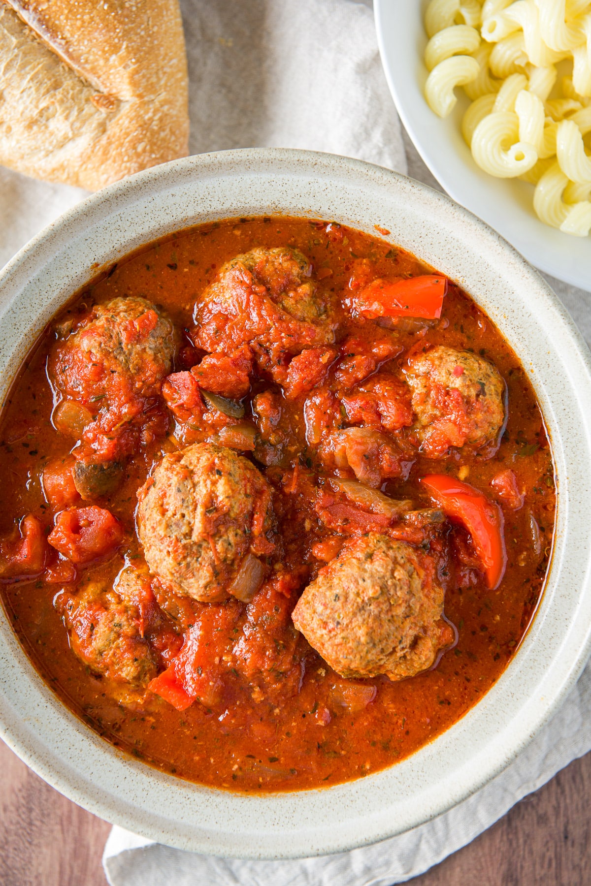 Overhead view of the big bowl with meatballs and sauce with some bread and pasta