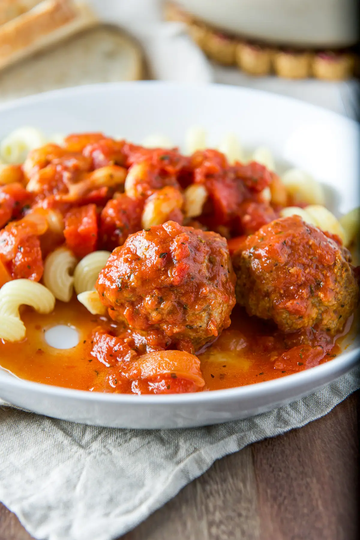 Close up of two meatballs with pasta in the back