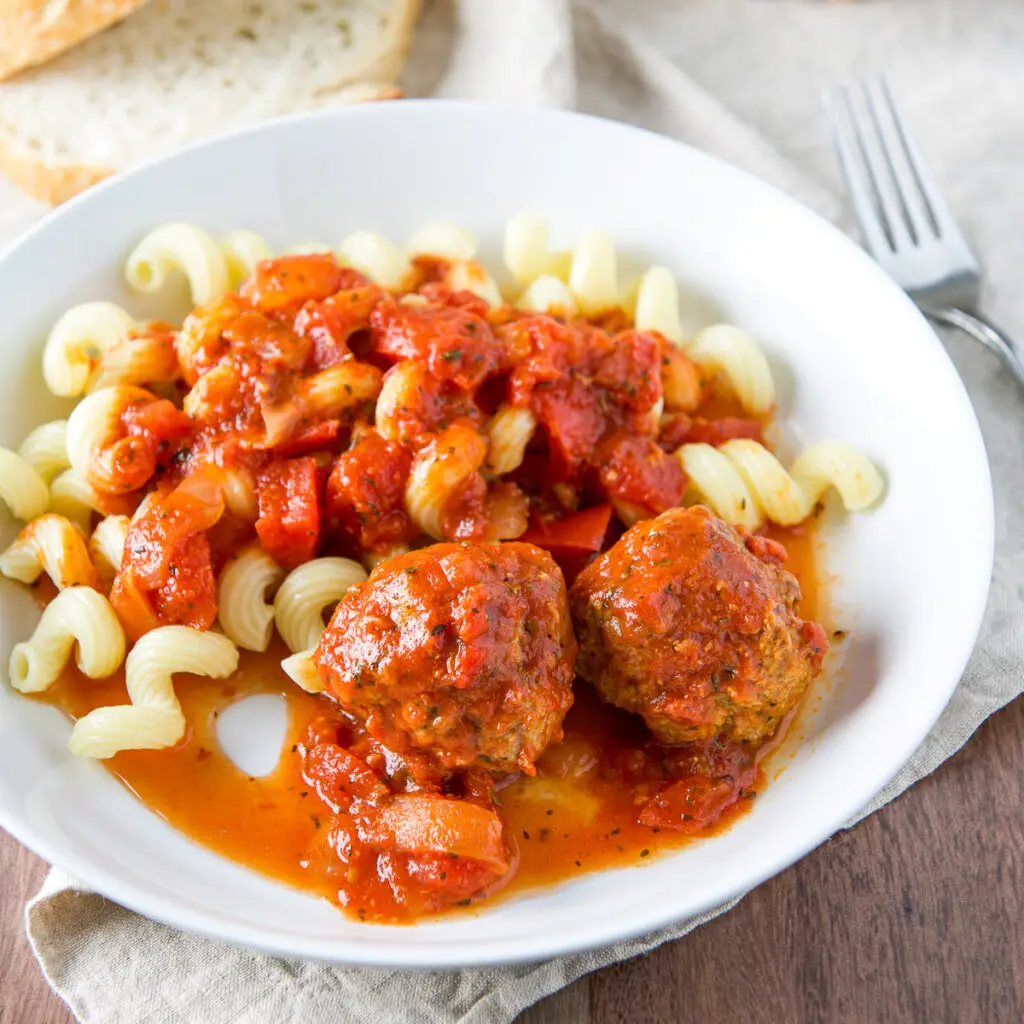 White deep dish with two meatballs, sauce and pasta - square