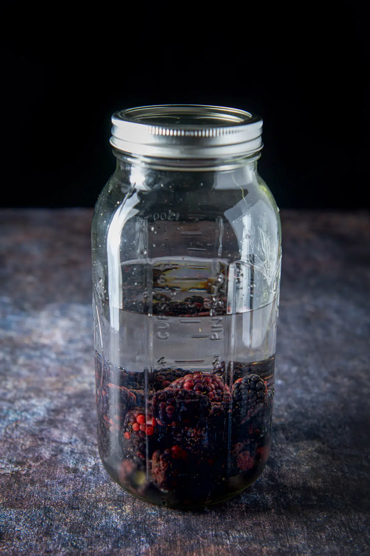 A capped jar with blackberries and vodka ready to be infused