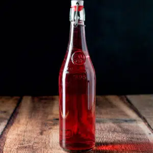 A wooden table with a bottle of raspberry vodka