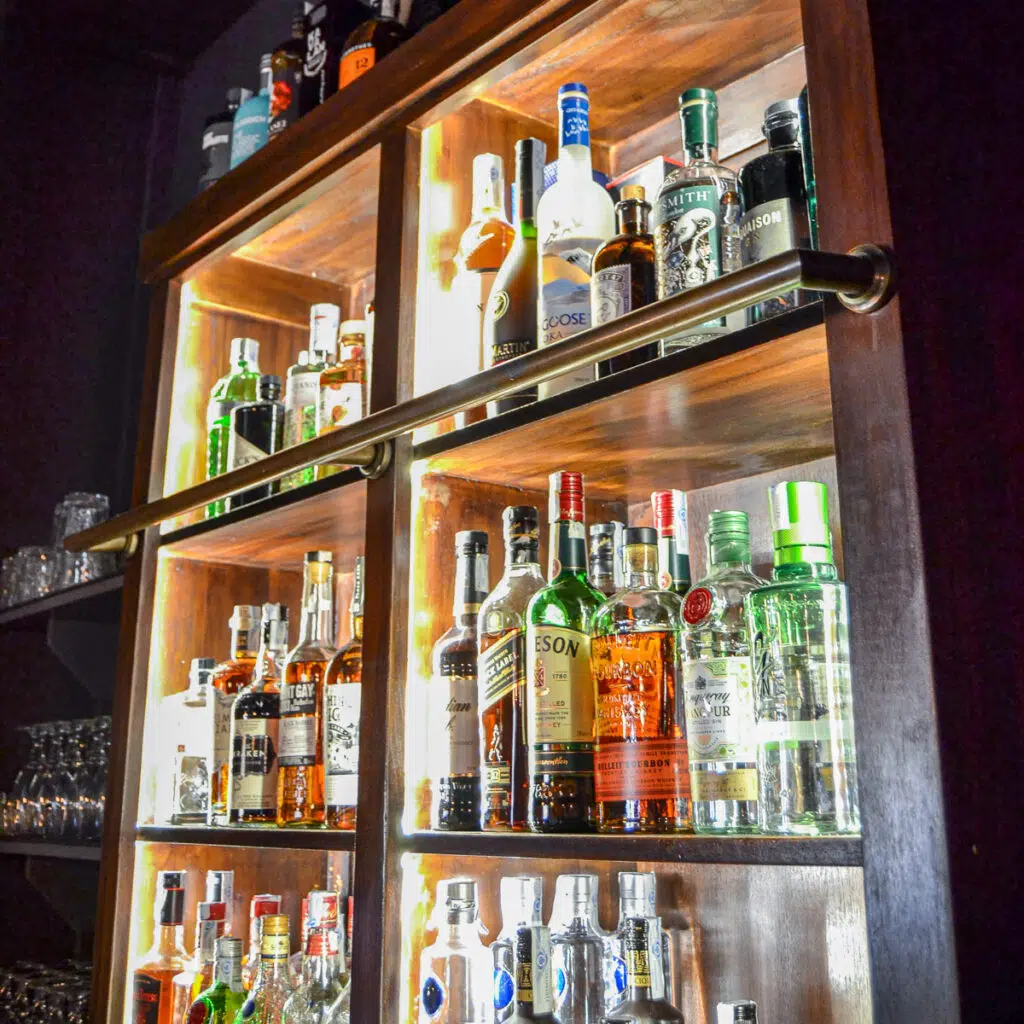 Wooden cabinet with bottles of alcohol on them - square
