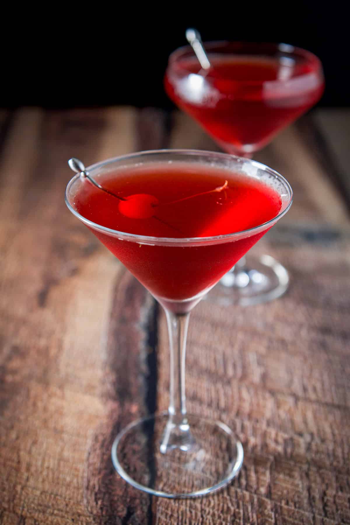 A cherry on a pick in the martini glass filled with the vampire kiss