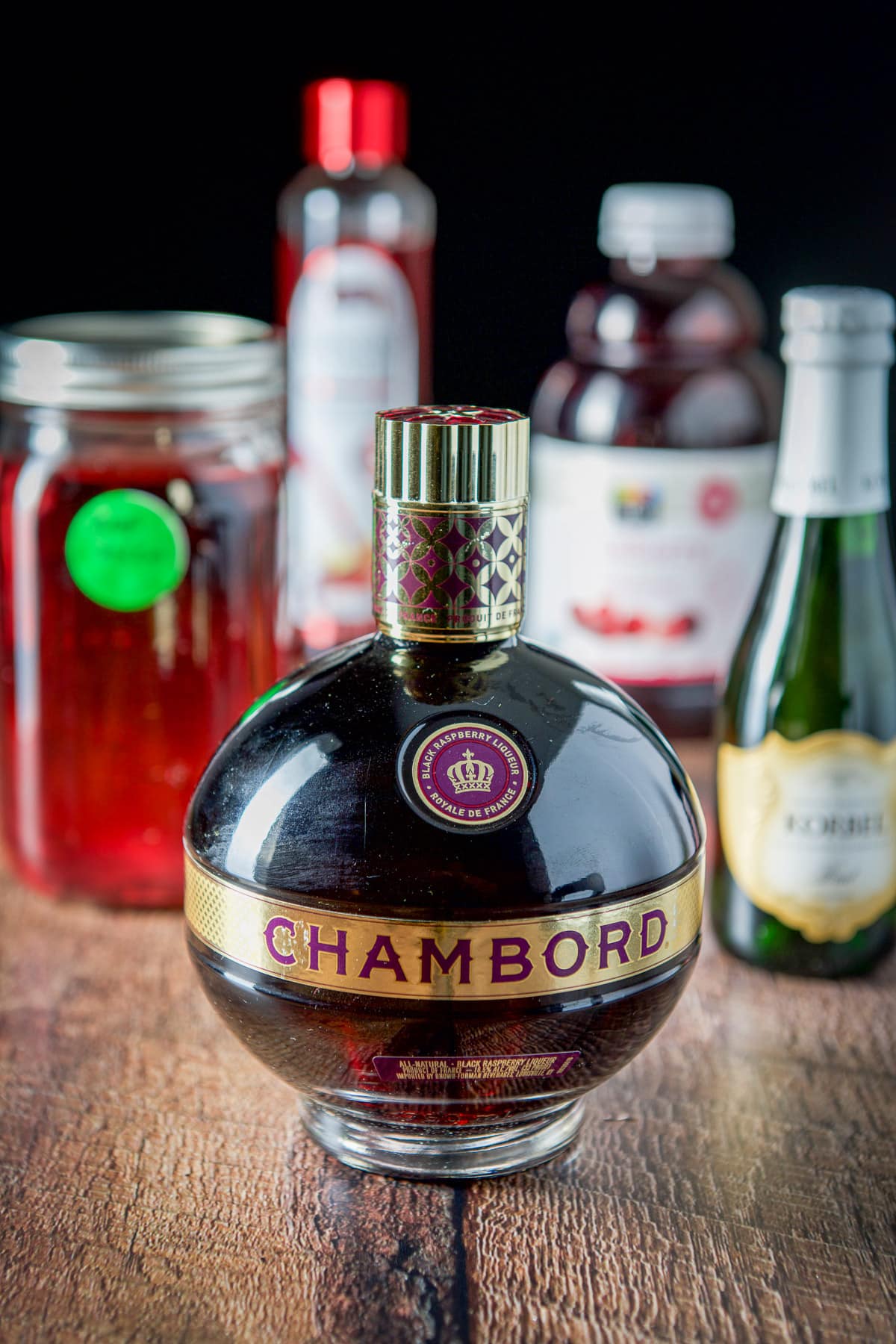 Chambord, raspberry vodka, cranberry juice, grenadine and champagne on a wooden table
