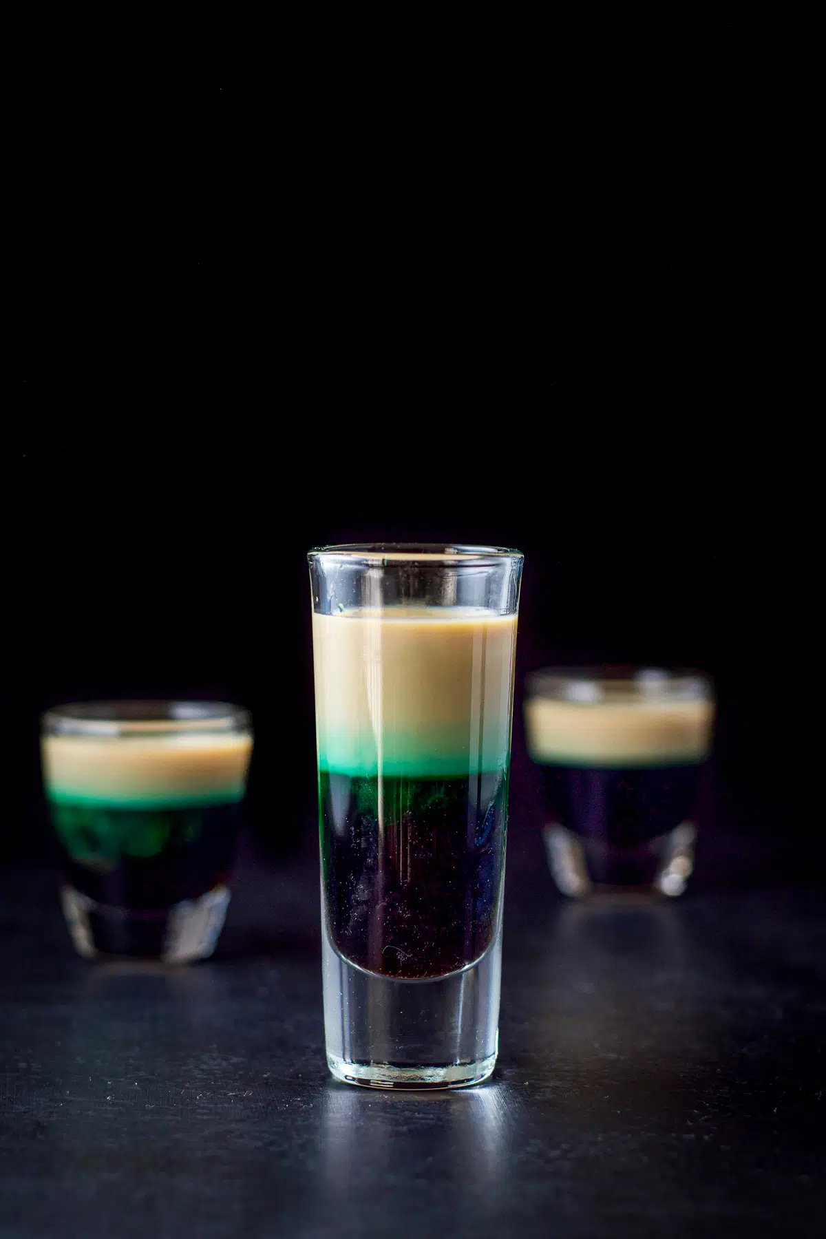 three shot glasses with brown, green and beige liquid in it
