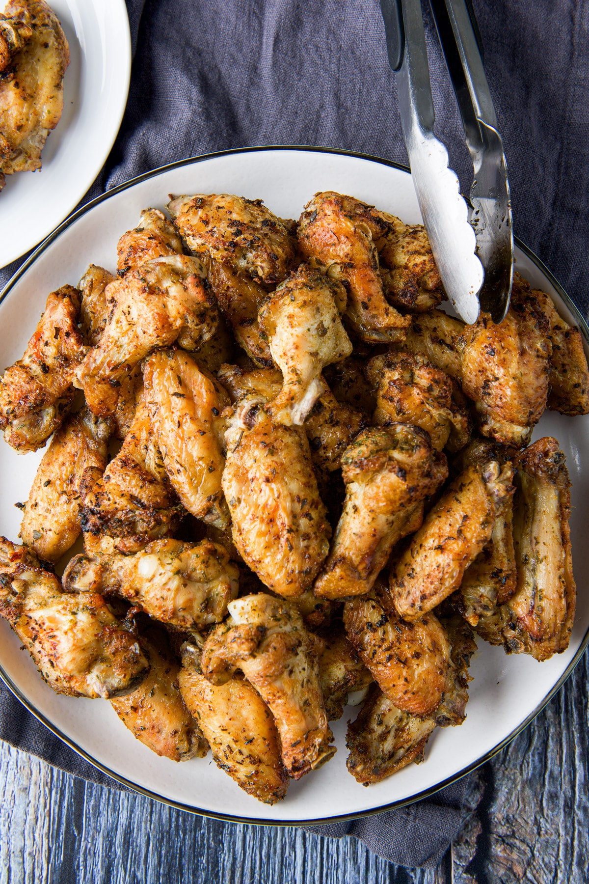 Overhead view of a platter of wings with a tongs off the side