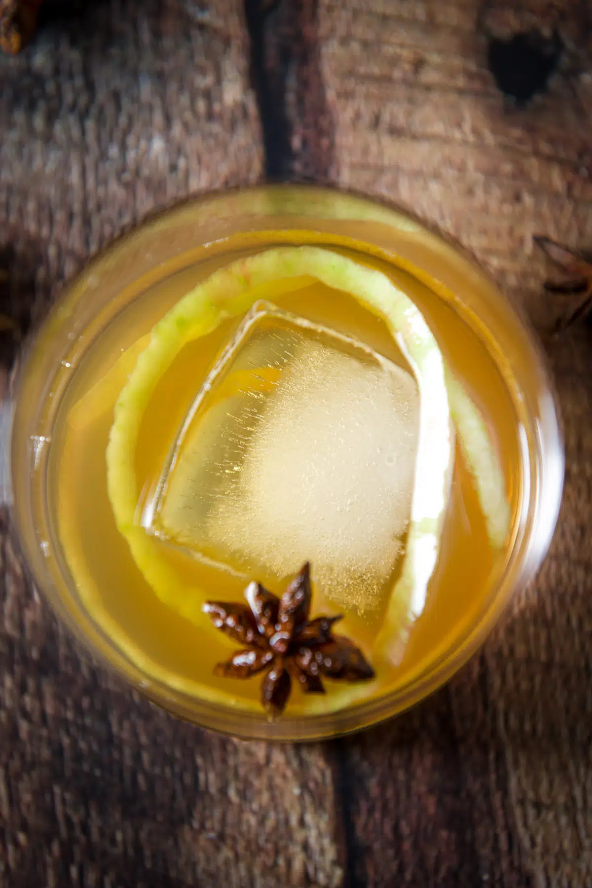 Overhead view of the apple cocktail with a big ice cube and star anise floating