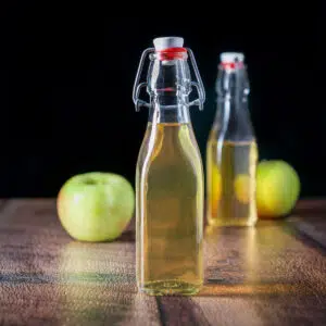 Two bottles with apple vodka with two apples on a wood table