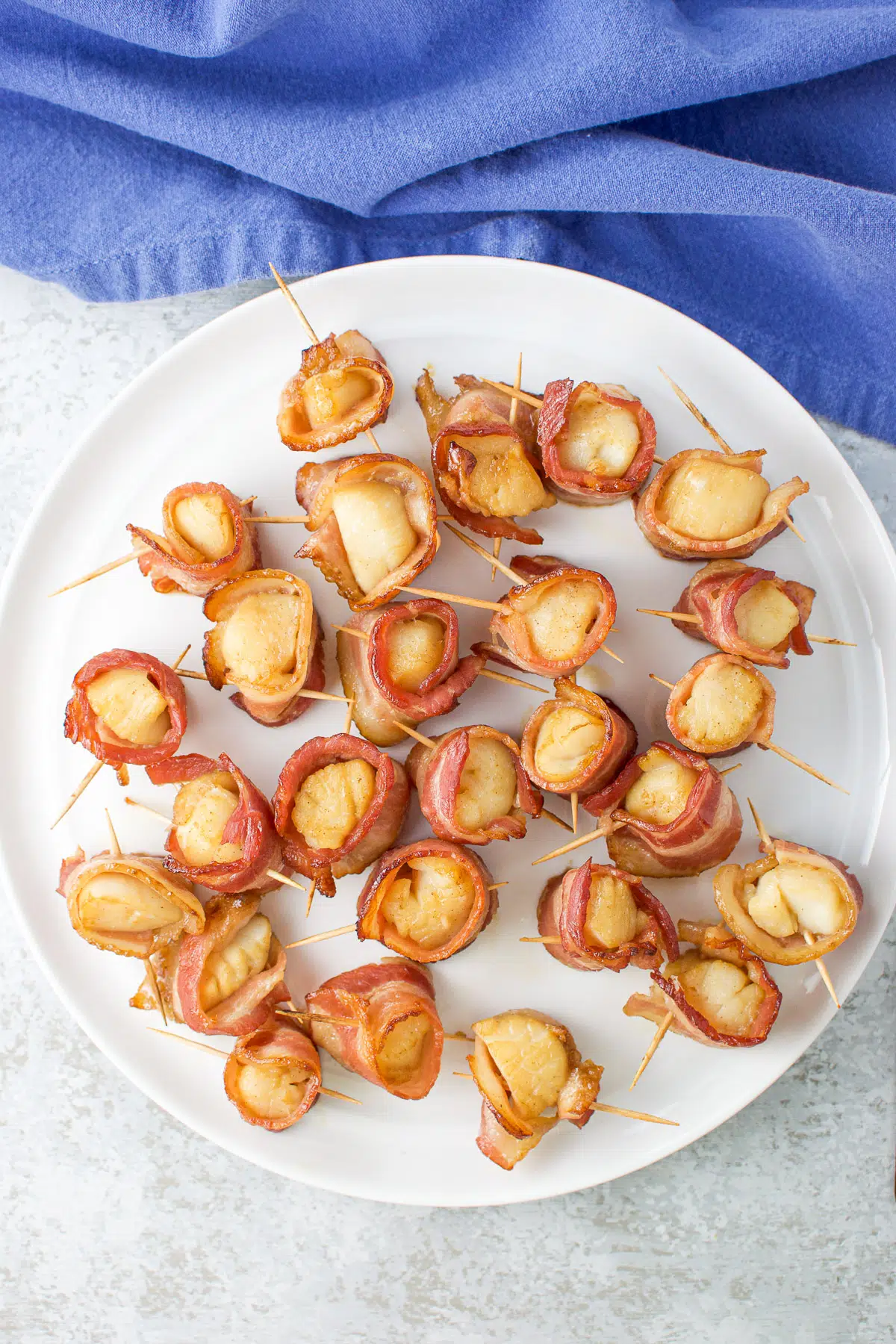 Overhead view of bacon wrapped around scallops on a white plate