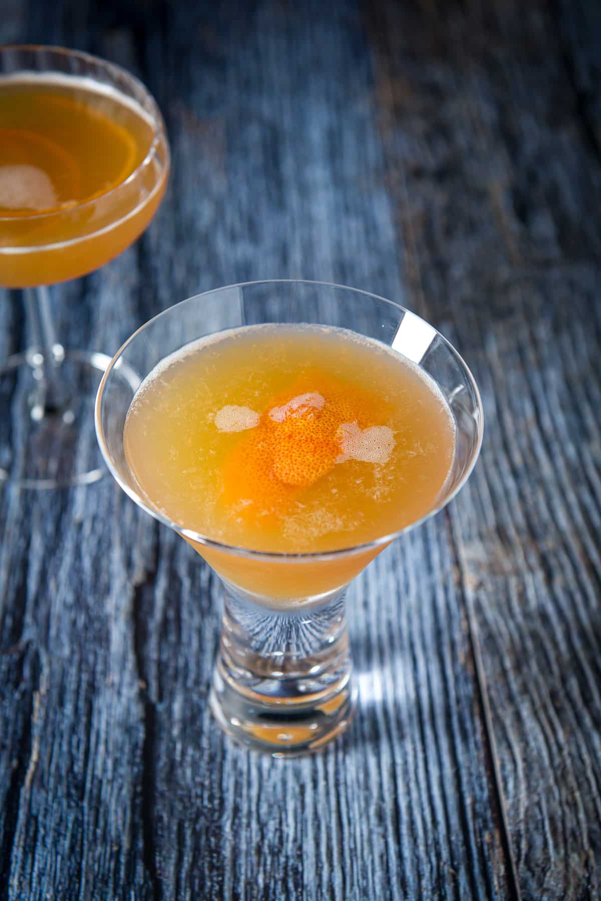 Martini glasses filled with the cocktail with orange twists in them