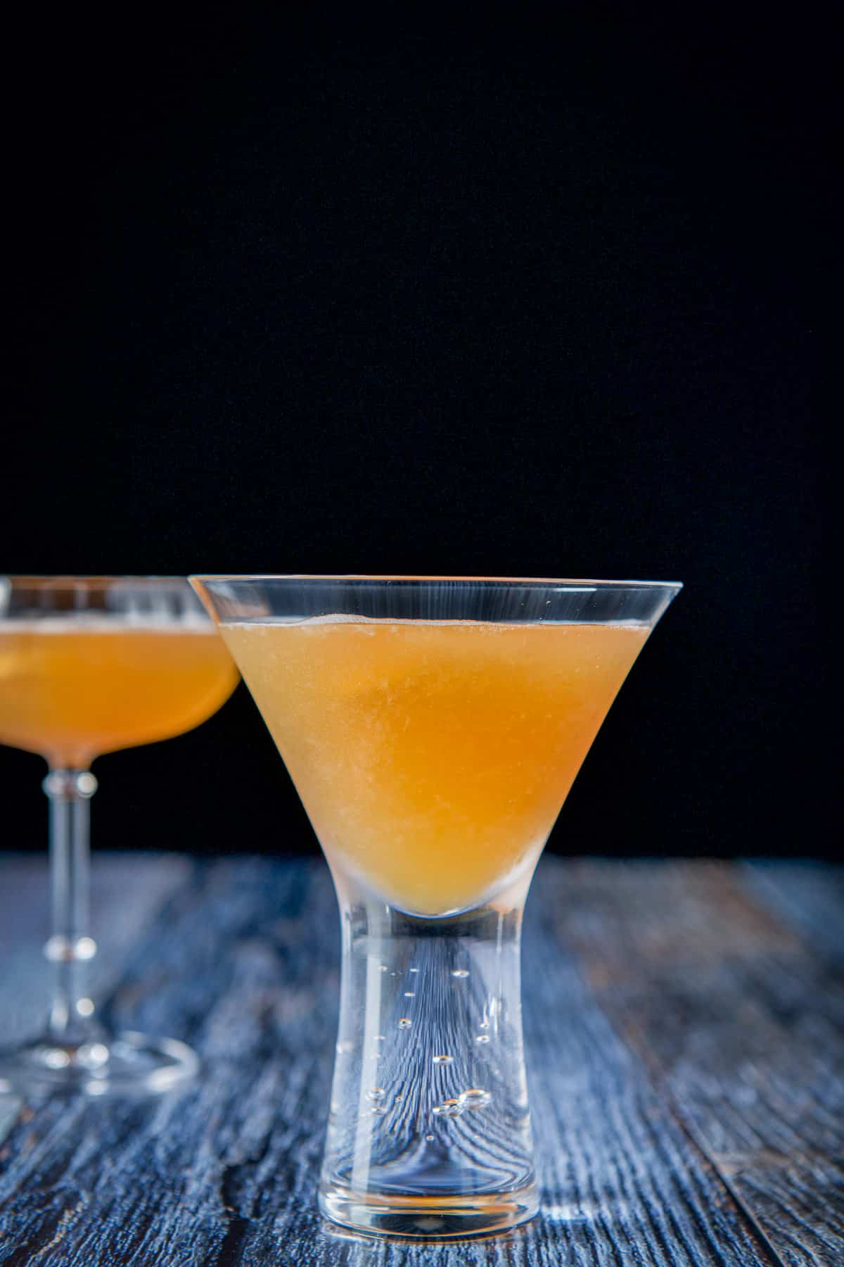 Vertical view of the martini glass filled with the drink with a coupe glass in the back