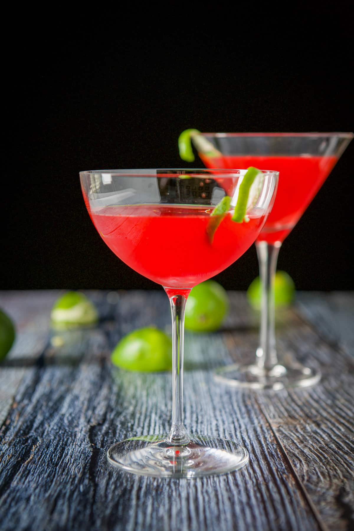 Vertical view of the bowl glass with a lime twist on the edge of it with the red drink