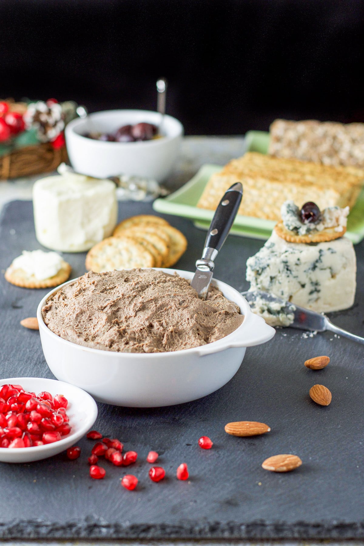 A white bowl with the pate in it with lots of appetizer foods around it