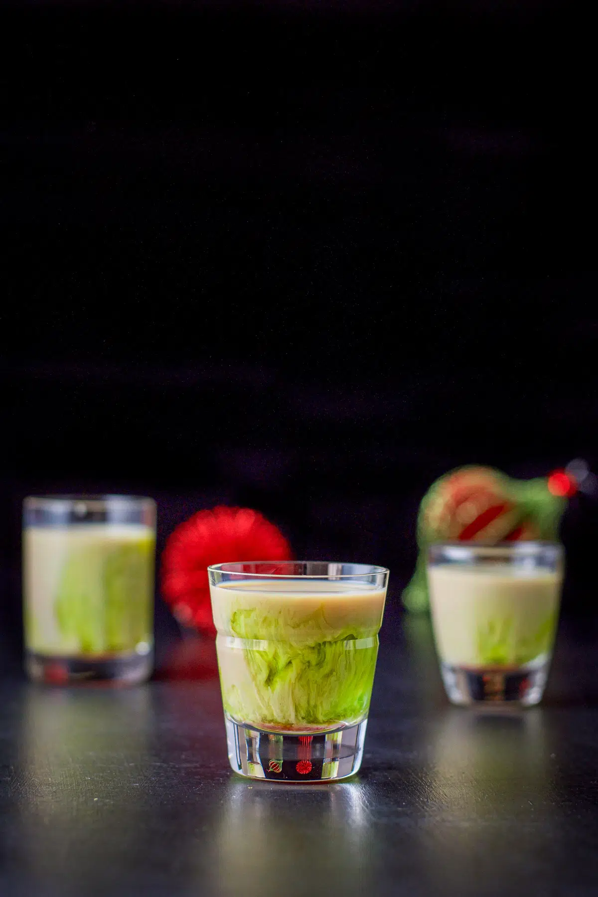 three glasses filled with a tan and green layered shot