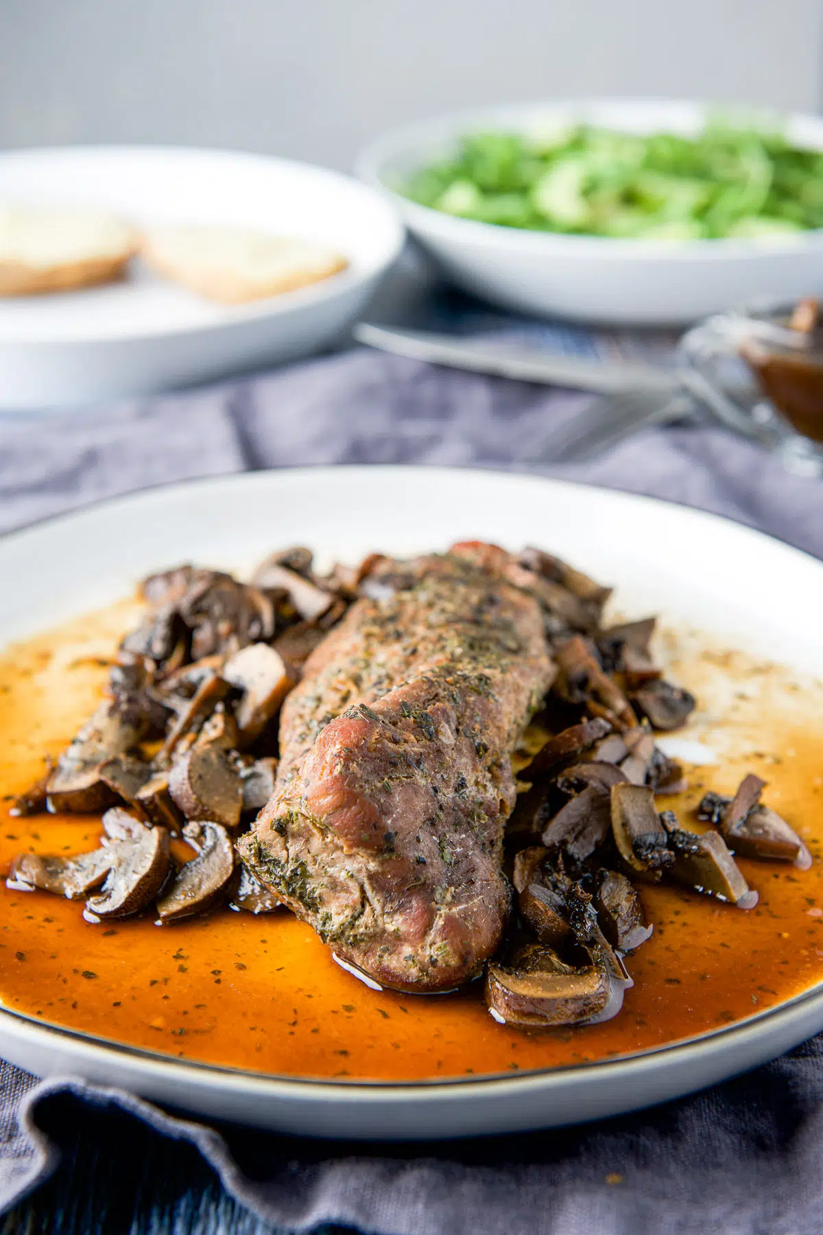 The tenderloin on a white plate with marinade and mushrooms