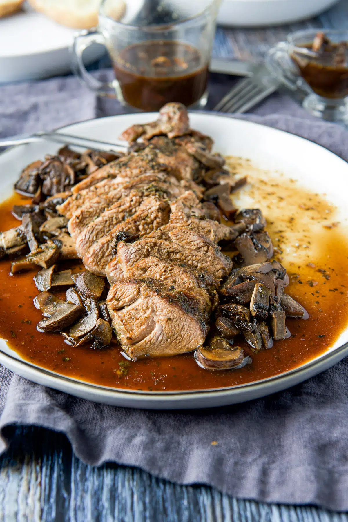 Tenderloin cut in slices with marinade on it and mushrooms on the side