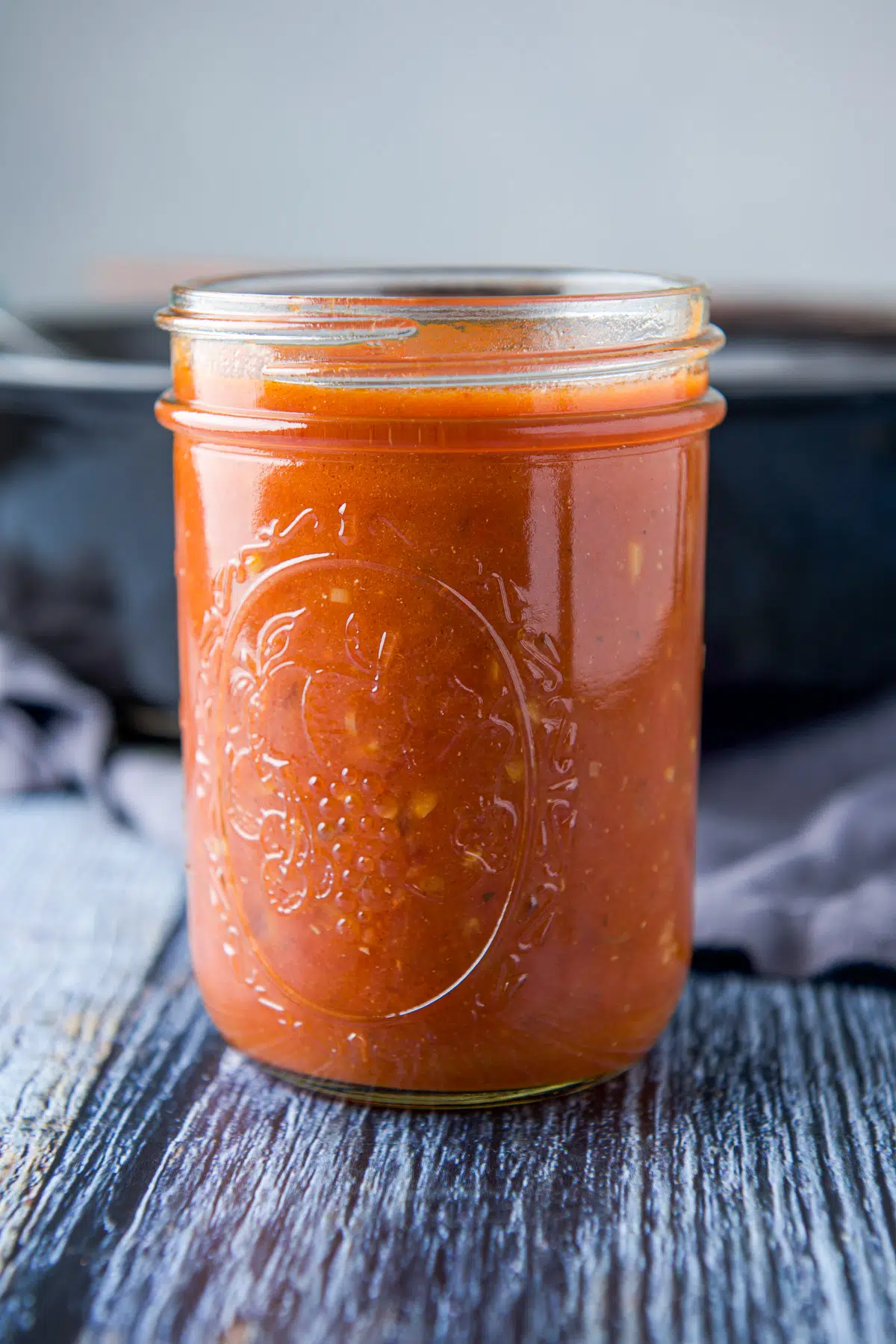 Vertical view of the pasta sauce in a jar with a pan in the background
