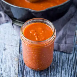 Pasta sauce in a jar with a pan of it in the back
