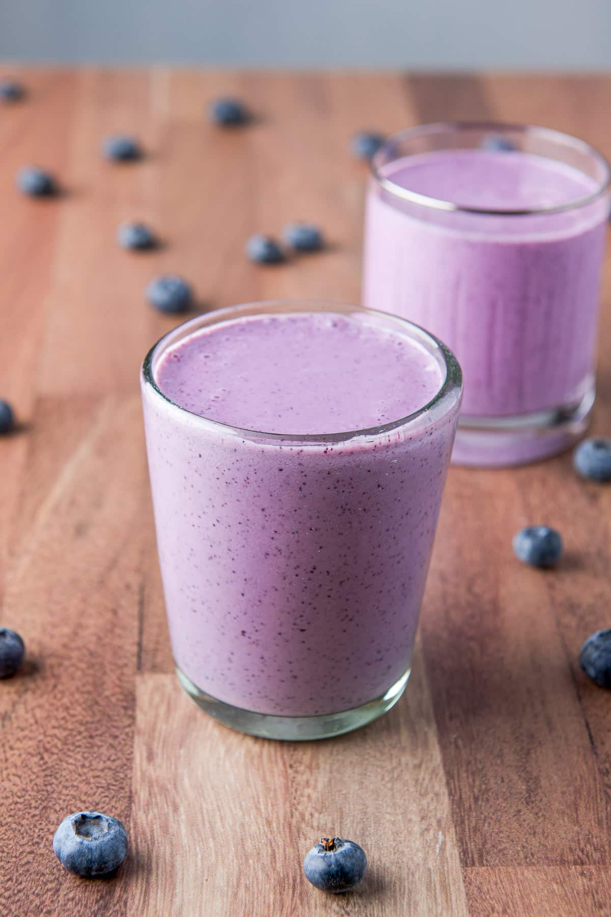 A double old fashioned glass with a creamy blue smoothie in front of another glass