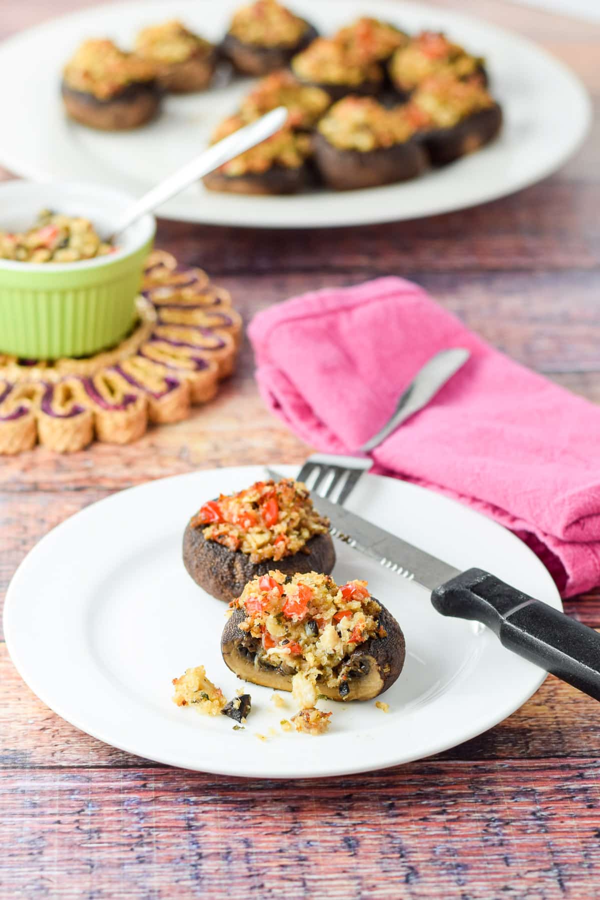 A different view of two crab mushrooms on a plate with a bigger plate in the background - one of the mushrooms has a slice out of it