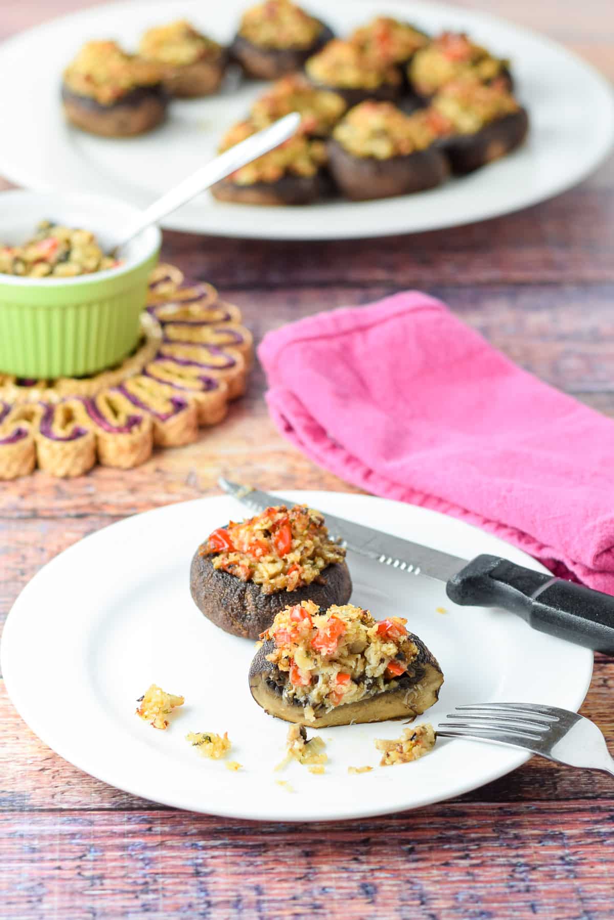 two crab mushrooms on a plate with a bigger plate in the background - one of the mushrooms has a slice out of it