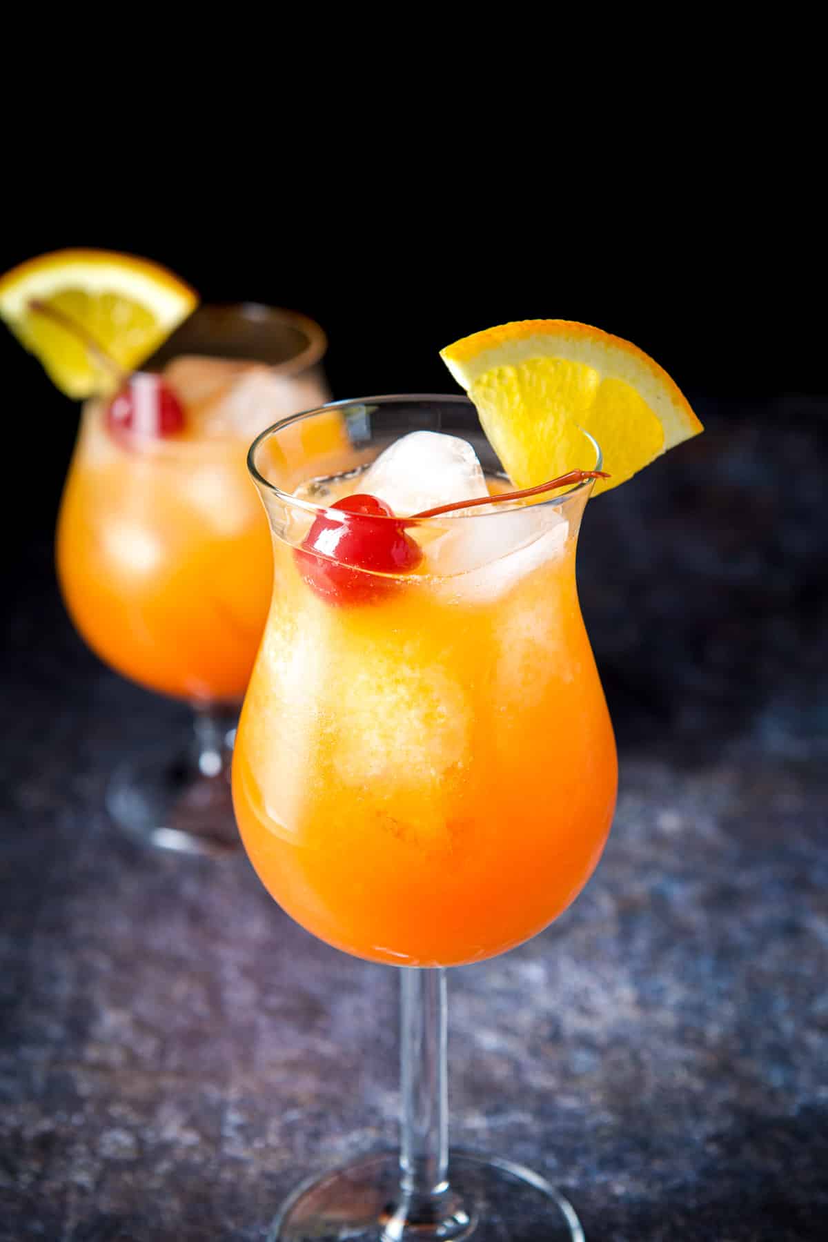 The taller tulip glass filled with the orange and red cocktail